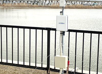 河川沿いの柵に設置されたアルフィオパワー屋外用電源BOXの使用例